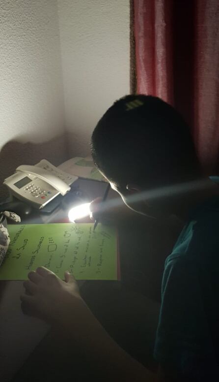 Decenas de niños y adolescentes del barrio hacen los deberes de clase con la luz de una linterna.