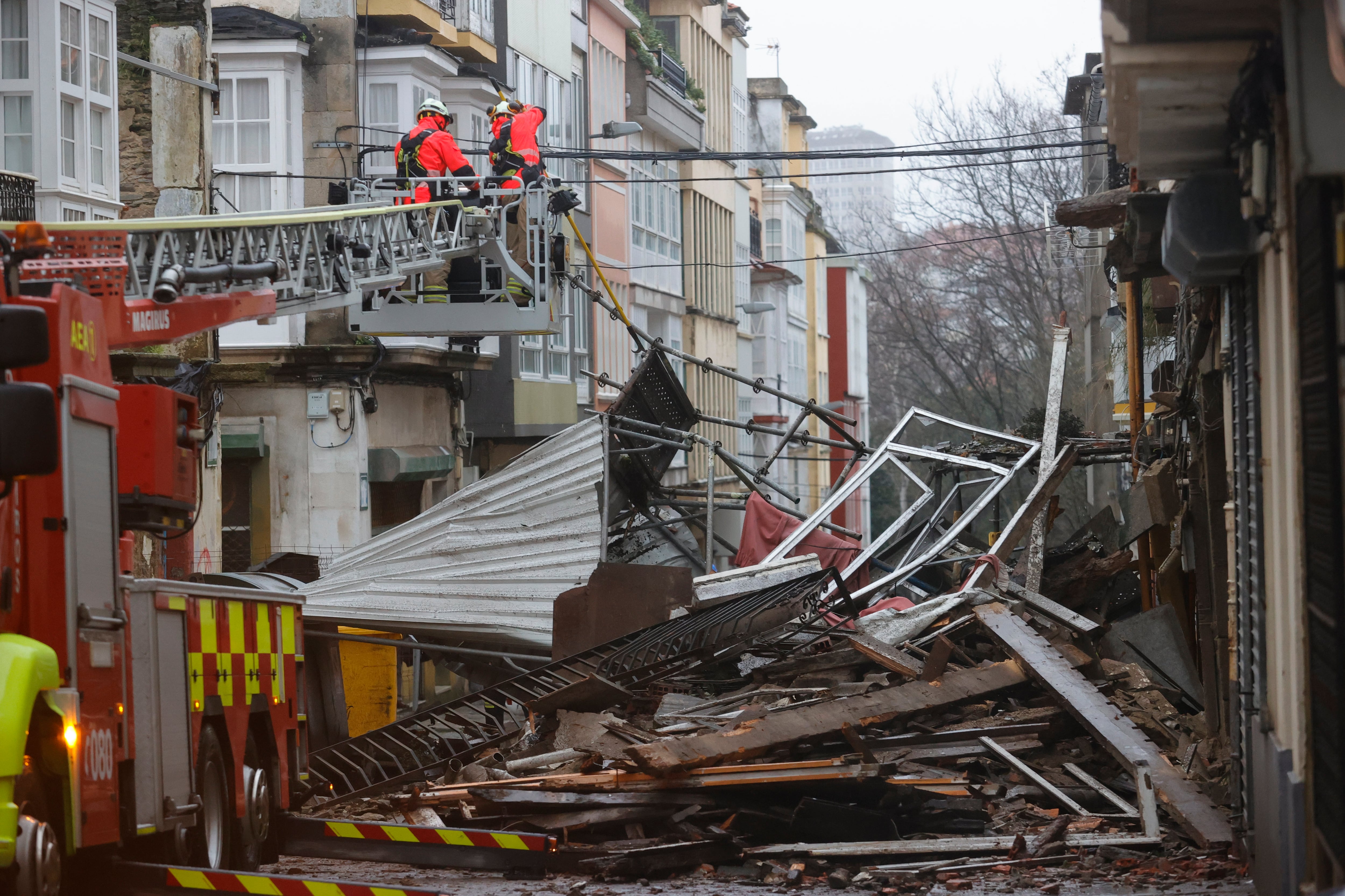 FERROL, 16/01/2023.- Efectivos de emergencias y equipos del servicio de Bomberos inspeccionan la zona en la que se ha producido el desplome de la fachada de un edificio de la calle Carlos III, en el barrio ferrolano de Esteiro, sin que se registraran heridos, a consecuencia del temporal, este lunes. EFE/ Kiko Delgado
