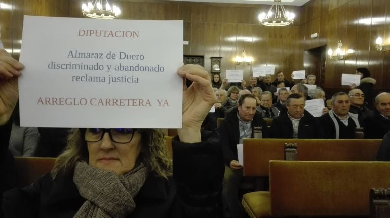 Una vecina de Almaraz muestra un mensaje a favor de la carretera en el Pleno de la Diputación de diciembre de 2017