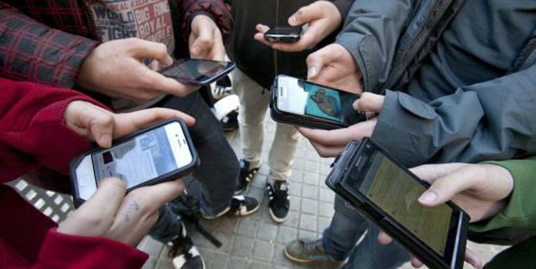 Varios adolescentes consultan sus teléfonos móviles