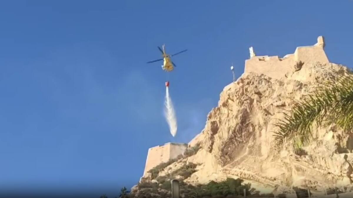El helicóptero del Consorcio de Bomberos sofoca un fuego en la muralla del Castillo de Santa Bárbara