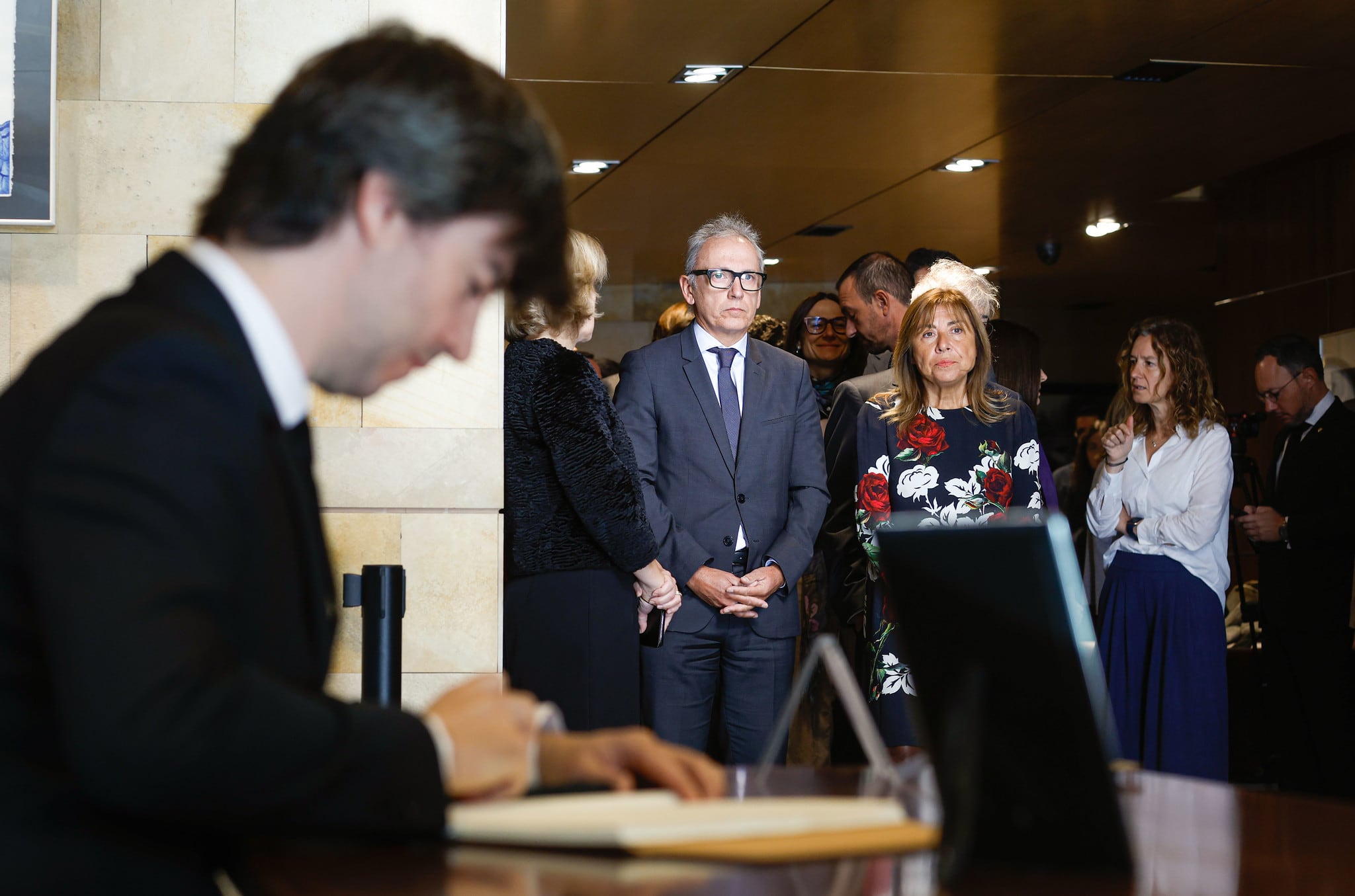 Carles Ensenyat signa el llibre de condol mentre altres autoritats esperen a l'edifici del Govern.