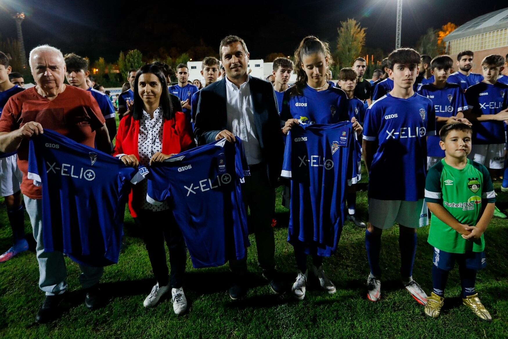 El presidente del Villena C.F., Juan Mateo Melenchón; la concejala de Deportes de Villena, Maite García; y el responsable de Desarrollo de X-ELIO en la Comunidad Valenciana, José Enrique Pardo, muestran las nuevas camisetas de los equipos de fútbol.