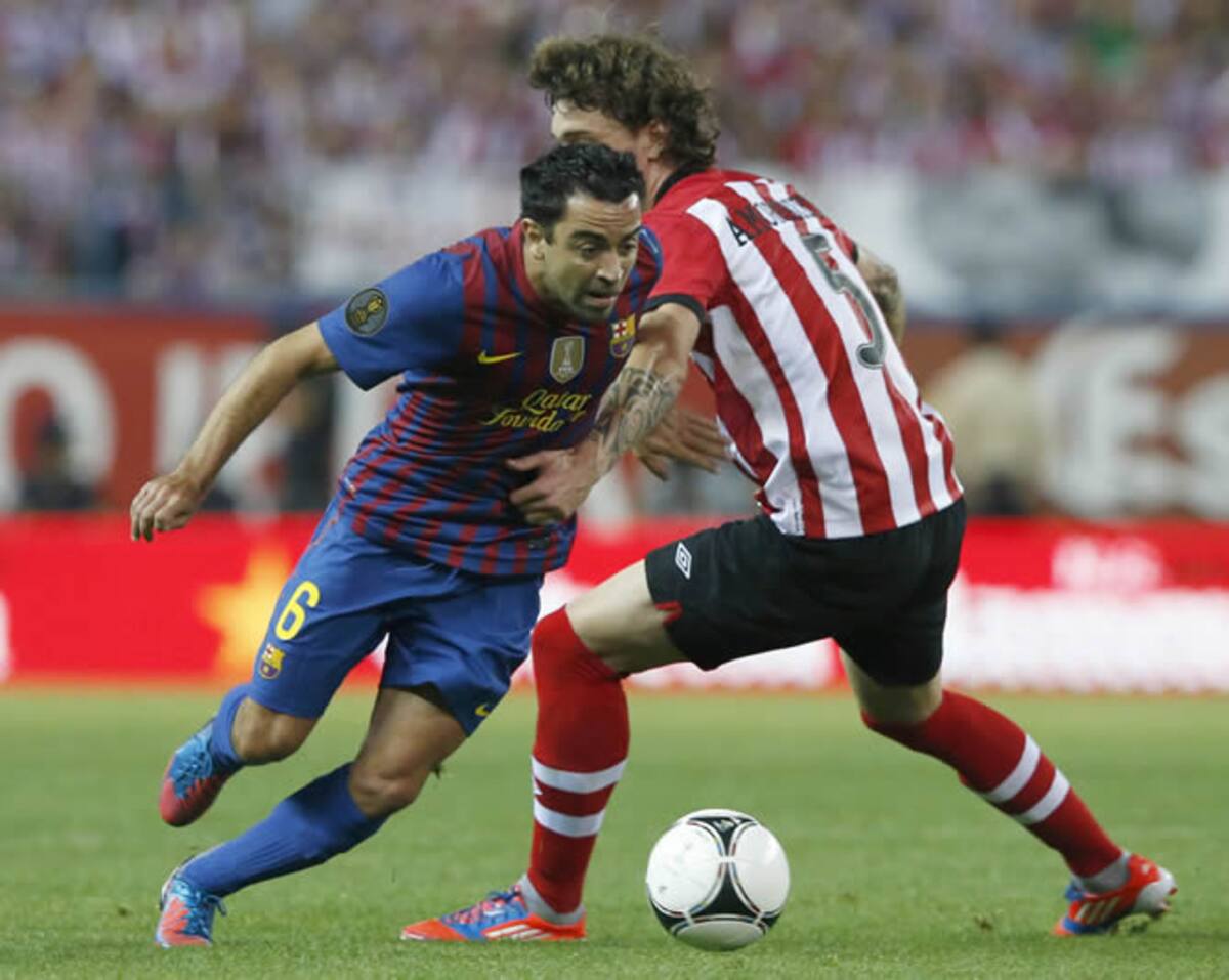 El defensa del Athletic de Bilbao Fernando Amorebieta (d) pelea un balón con el centrocampista del FC Barcelona Xavi Hernández, en la final de la Copa del Rey de fútbol que se disputa esta noche en el estadio Vicente Calderón de Madrid. | <a href="http://