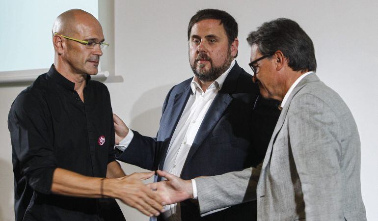 El candidato numero 1 de Junts pel Sí, Raul Romeva, saluda al president de la Generalitat y candidato numero 4, Artur Mas, en presencia del candidato numero 5, Oriol Junqueras, durante el acto de presentación del programa electoral de la coalición.