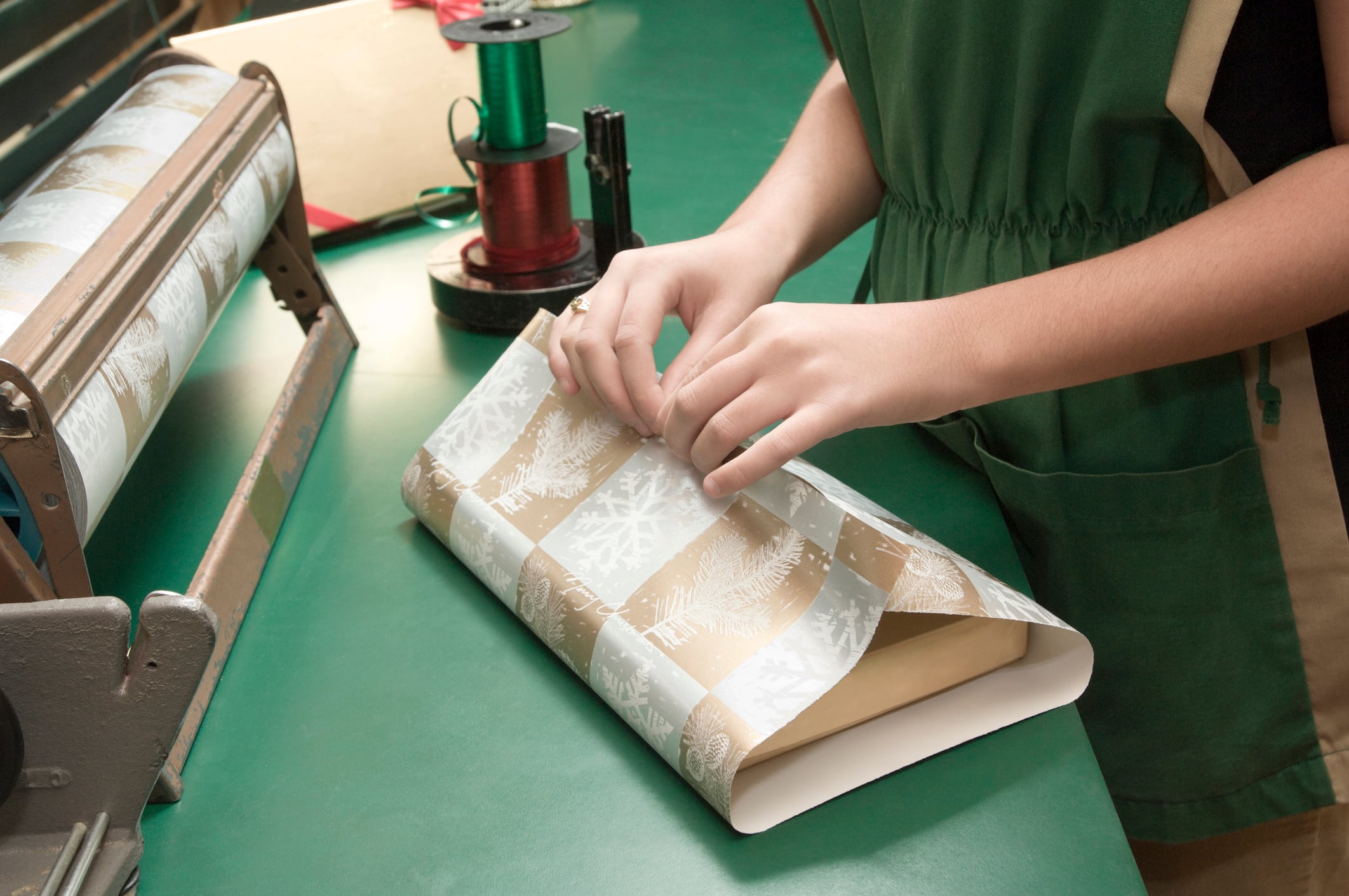 Una mujer, en un negocio, envolviendo un producto en papel de regalo para Navidad