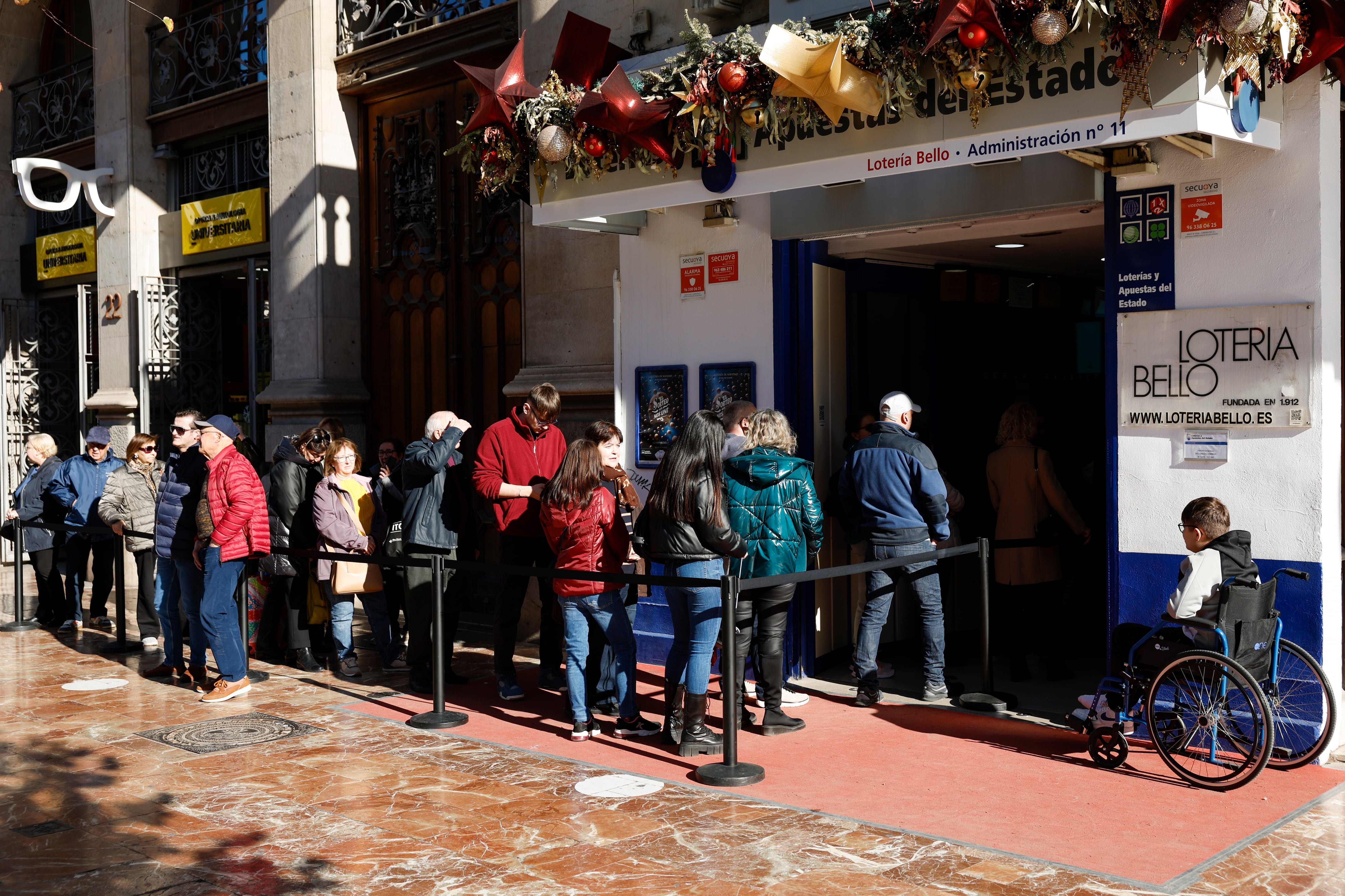 Varias personas hacen cola en una administración de lotería durante este viernes cuando las peticiones de lotería del Gordo de Navidad de València desde el resto de España se han disparado este año en las administraciones de la ciudad y de los municipios a consecuencia de la dana.