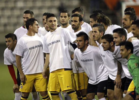 Los jugadores de L&#039;Hospitalet y del Atlético de Madrid lucen camisetas antiviolencia antes de comenzar el partido de ida de dieciseisavos de final de la Copa del Rey.