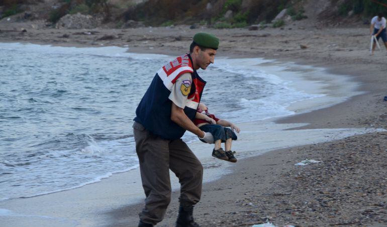 Un agente de la gendarmería turca recoge el cadáver del menor fallecido cauando intentaba llegar a Europa con su familia. 