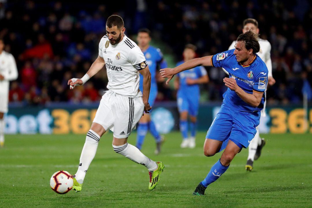 El delantero francés del Real Madrid Karim Benzema lucha con Ignasi Miquel, del Getafe CF