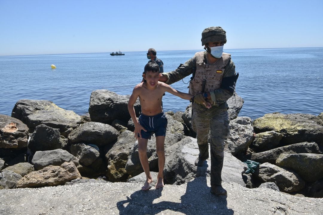 Un militar del ejército español ayuda a un menor migrante procedente de Marruecos a su llegada a Ceuta