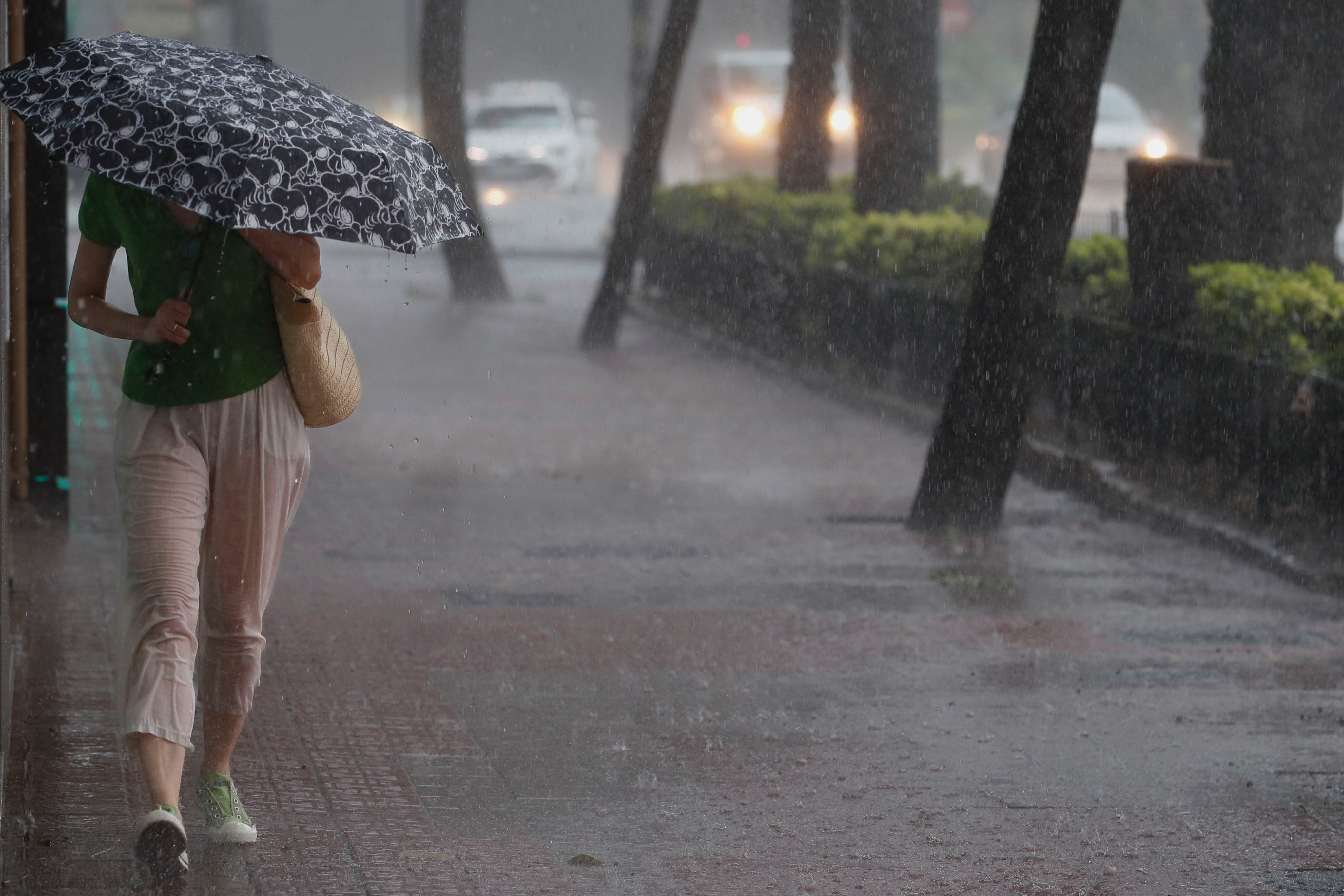 Una mujer camina por la acera bajo una intensa lluvia en València en una imagen de archivo.