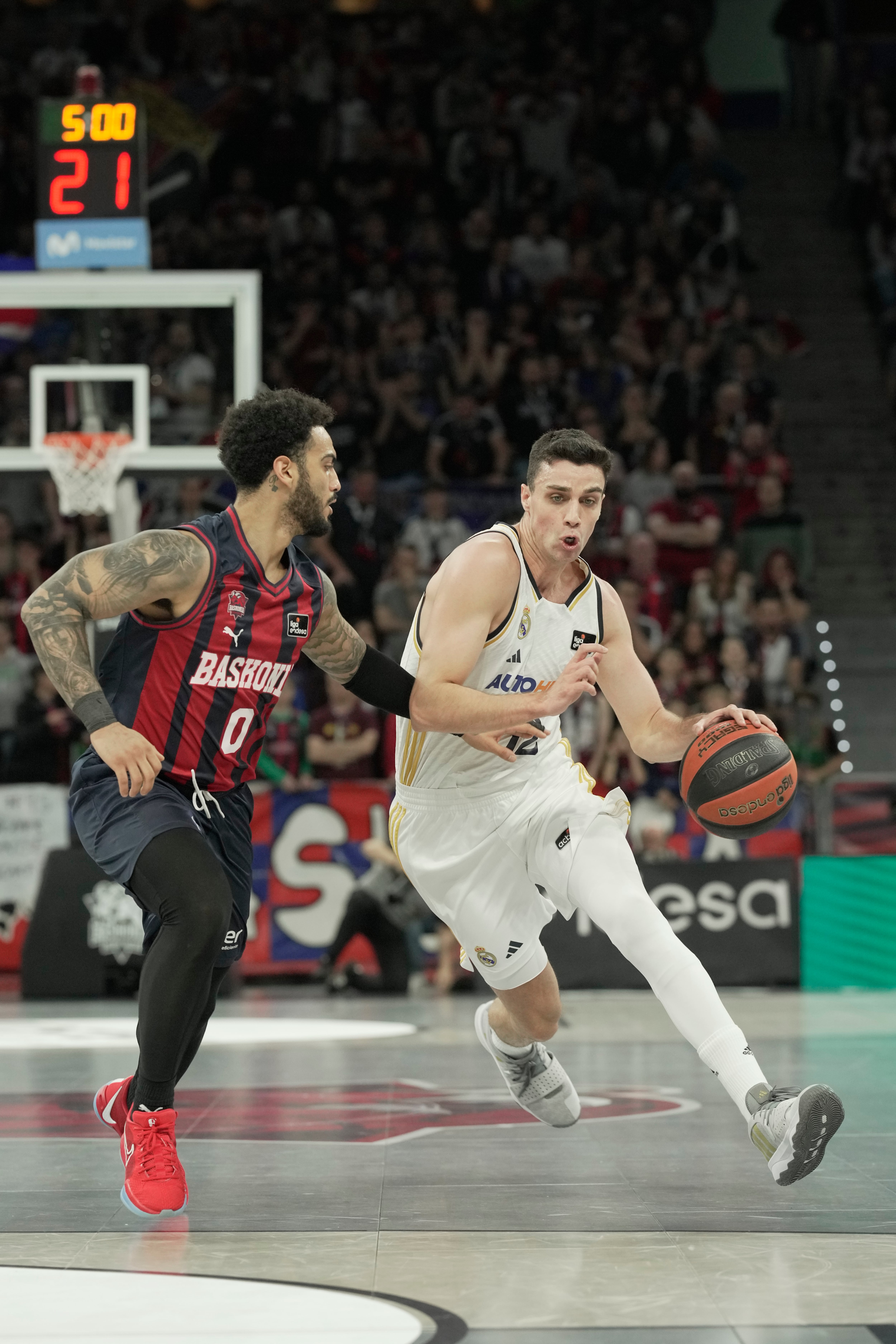 VITORIA-GASTEIZ , 07/01/2024.- El base español del Real Madrid Carlos Alocén bota el balón ante el base estadounidense del Baskonia Markus Howard (i) durante el partido de la Liga Endesa entre el Saski Baskonia y el Real Madrid disputado este domingo en el pabellón Fernando Buesa Arena de Vitoria-Gasteiz. EFE/ Adrián Ruiz Hierro
