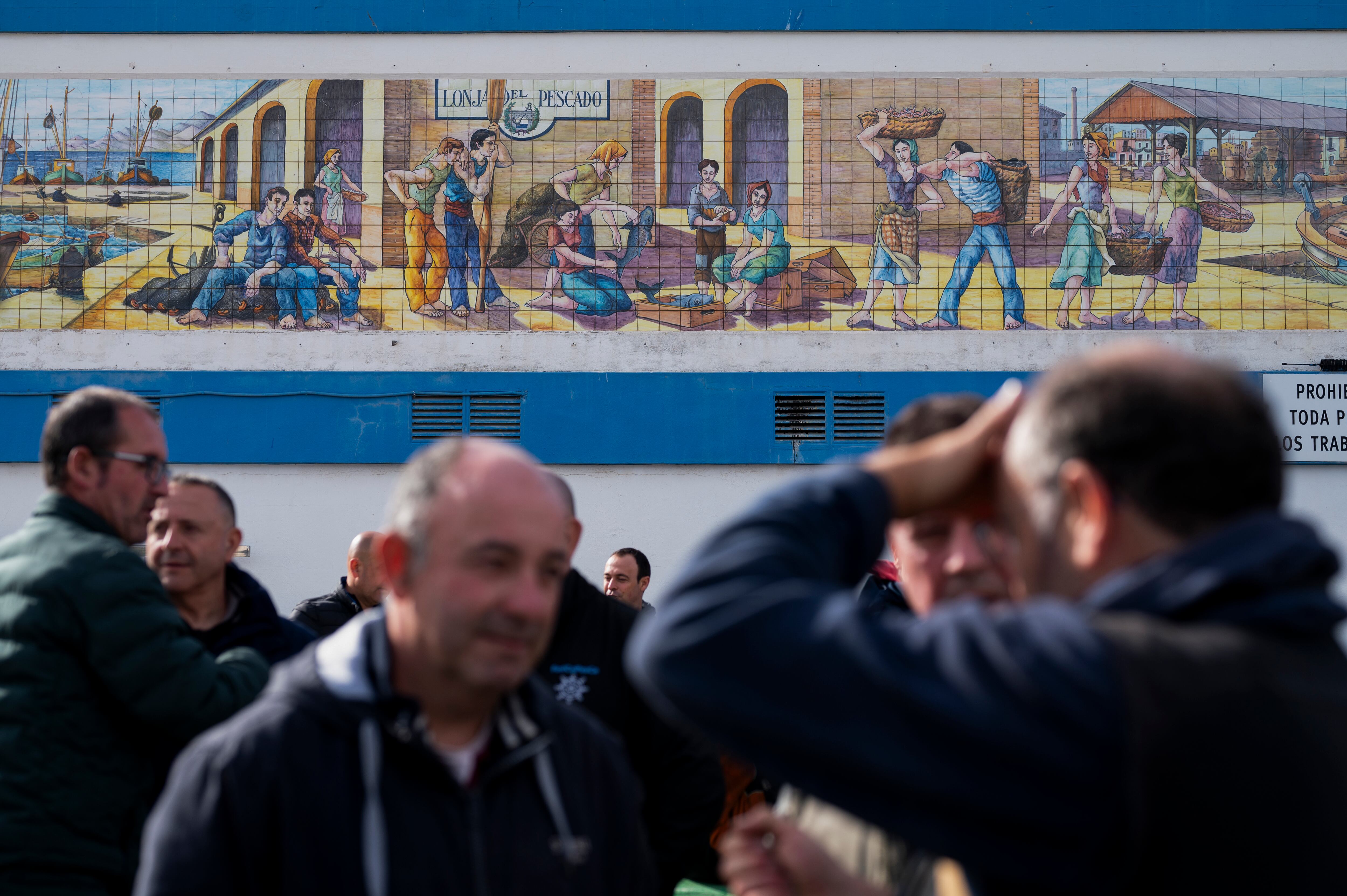 Un grupo de pescadores aguarda junto a la lonja del pescado cuando las 54 embarcaciones de arrastre de las cinco cofradías pesqueras de la provincia de Castellón se han quedado amarradas en puerto en señal de protesta ante el trato recibido por la normativa europea que les recorta los días de pesca y para sumarse a las reivindicaciones de los agricultores españoles. 