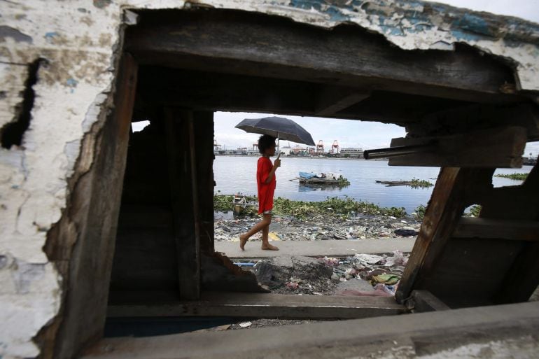 DEN13 MANILA (FILIPINAS) 05/12/2014.- Un filipino pasa tras un bote de pesca dañado mientras espera ser evacuado de una barriada de chabolas en el istrito de Baseco, Manila (Filipinas) hoy, viernes 5 de diciembre de 2014. El supertifón Hagupit, con viento