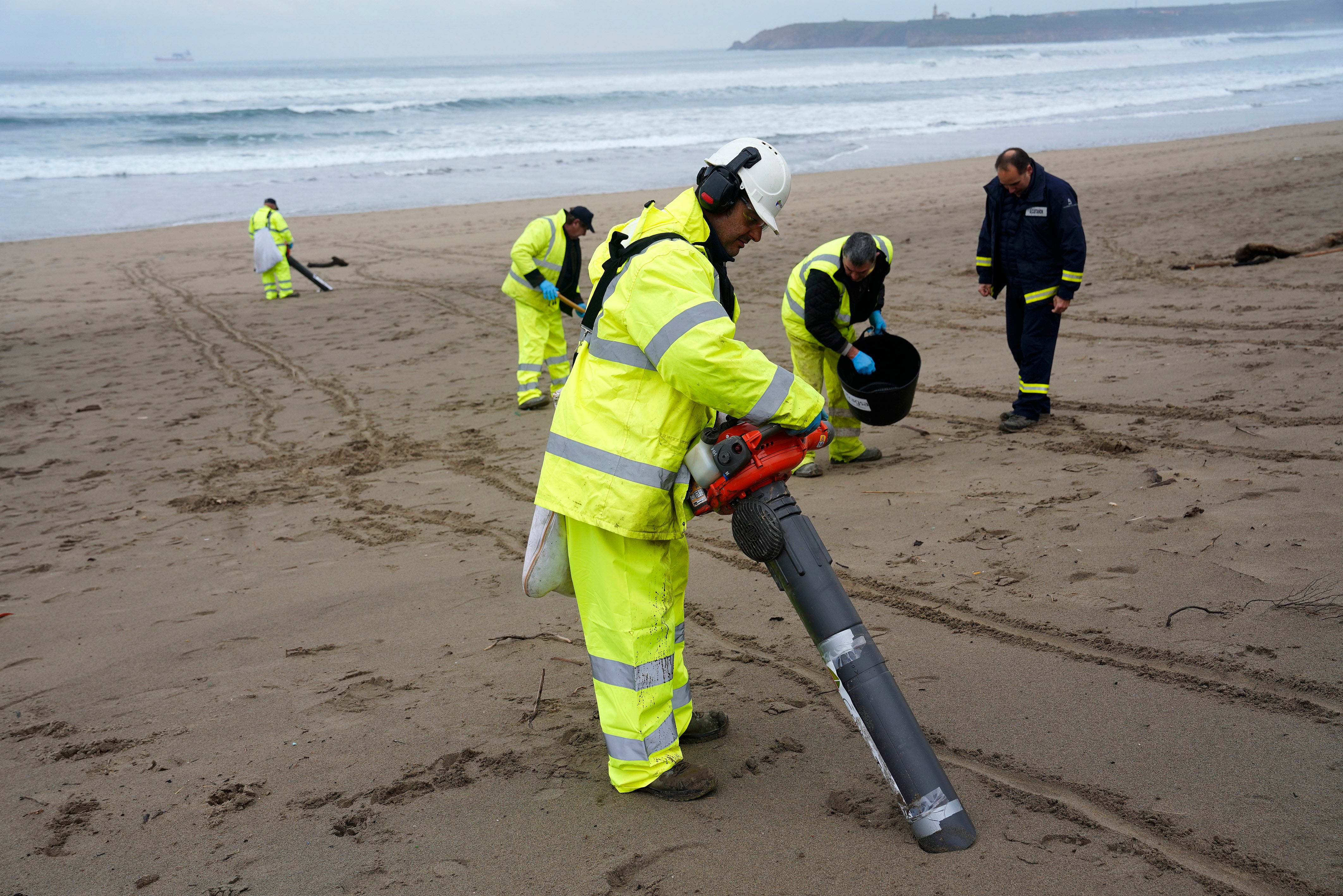 Operarios con aspiradores en la playa asturiana de Salinas. EFE/Paco Paredes