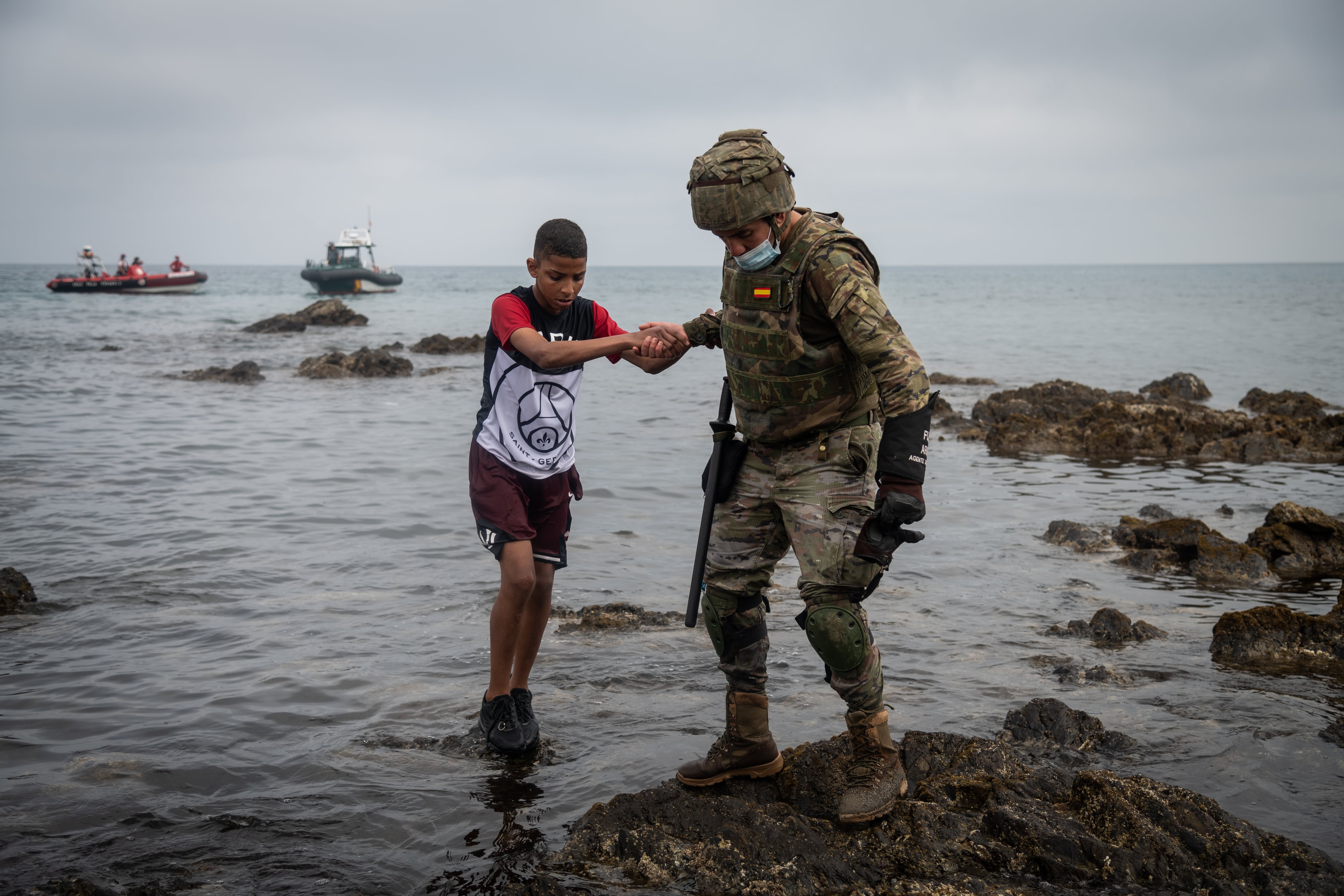 Un soldado ayuda a un menor a entrar en Ceuta en una imagen de archivo de la Playa del Tarajal