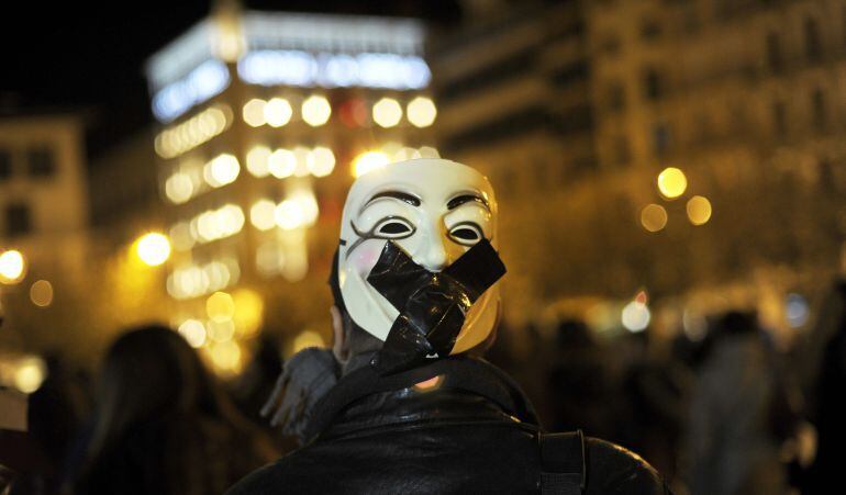 Un joven porta una careta con una mordaza, en una manifestación. 