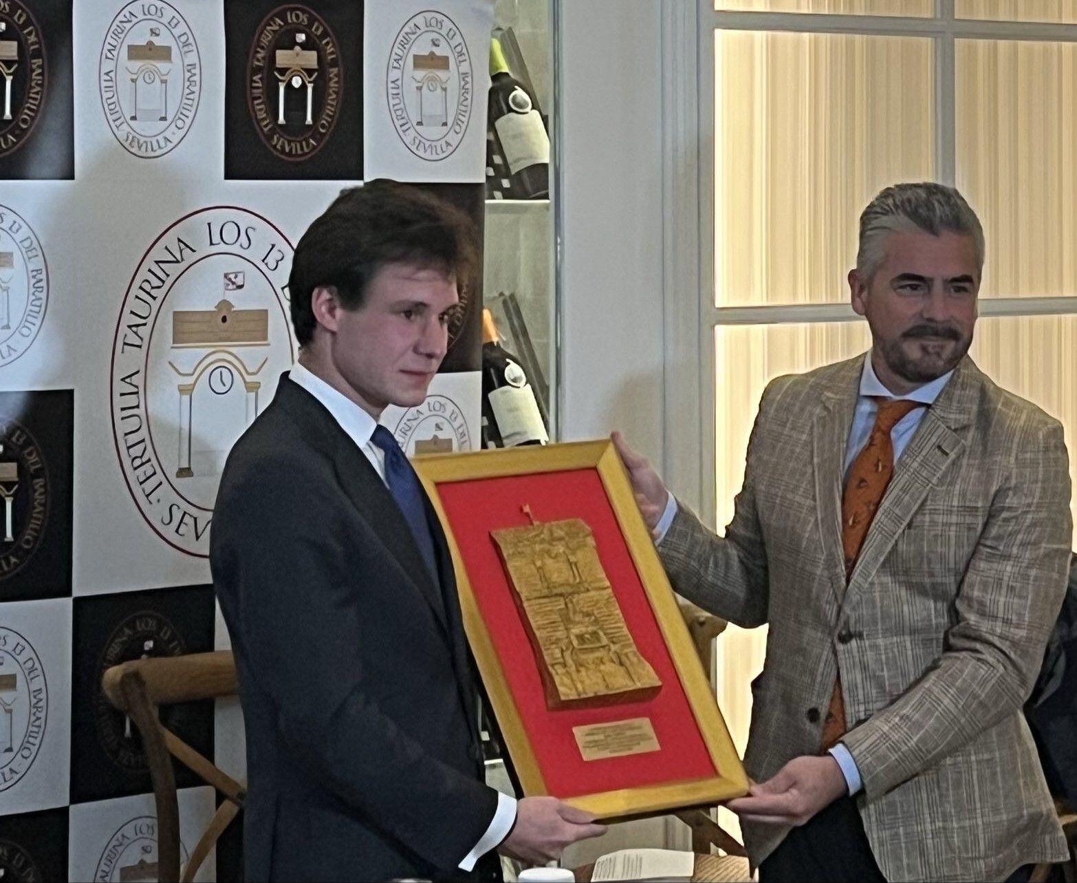 El torero Fabio Jiménez, a la izquierda, recibe de manos de Carlos Trejo, presidente de la Tertulia Taurina Los 13, el trofeo que le acredita como mejor novillero del año 2025 en Sevilla