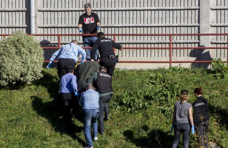 Personal de la funeraria y agentes de la Ertzaintza trasladan el cuerpo sin vida de una mujer que ha fallecido en Bilbao al caer por una ventana desde su vivienda.