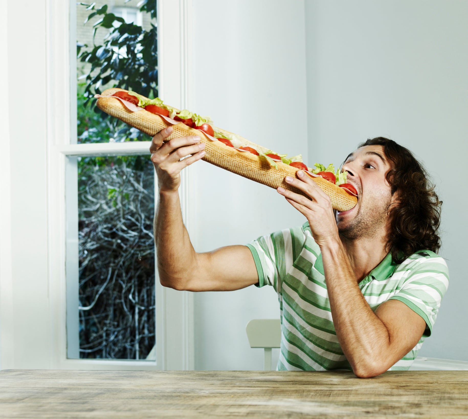 Un hombre comiendo un gran bocadillo.