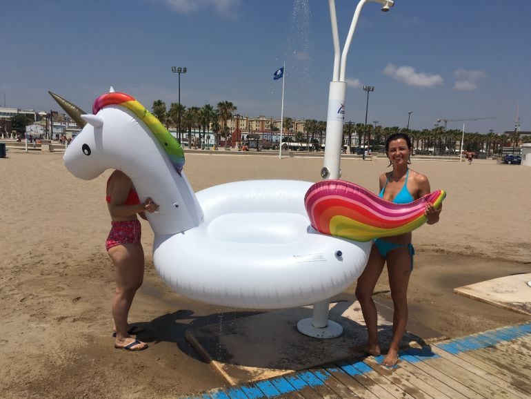 Dos mujeres llevan un flotador de unicornio en una playa