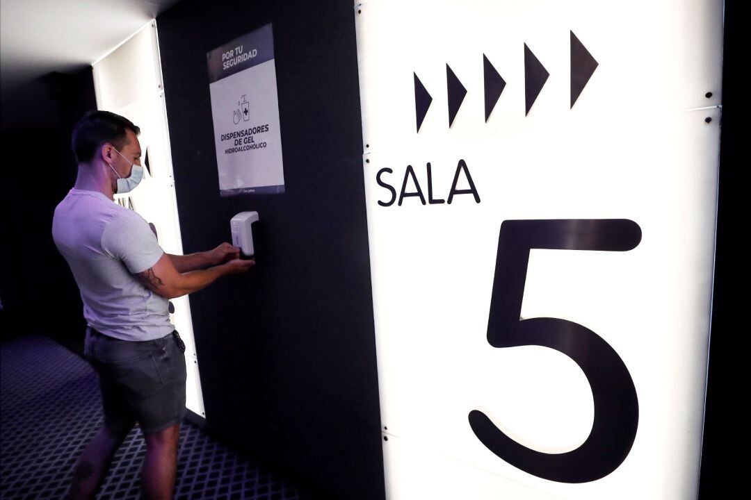 Una persona se desinfecta con gel las manos antes de entrar a una de las salas de los Cines Yelmo de Pamplona.