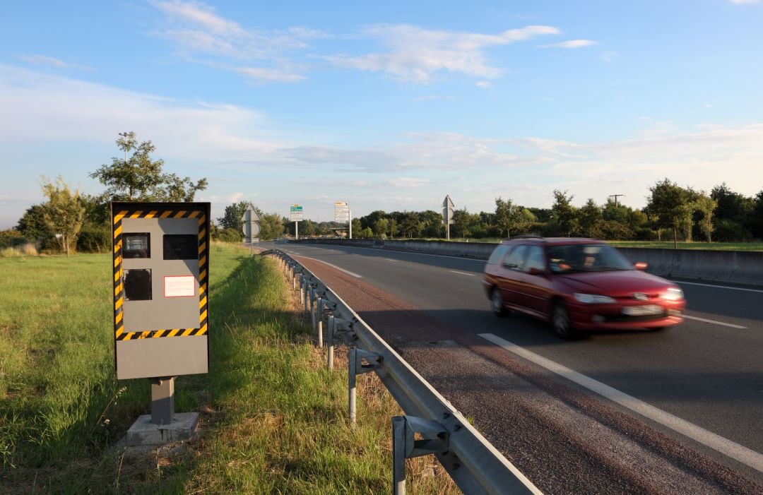 Un vehículo circula junto a un radar de velocidad.