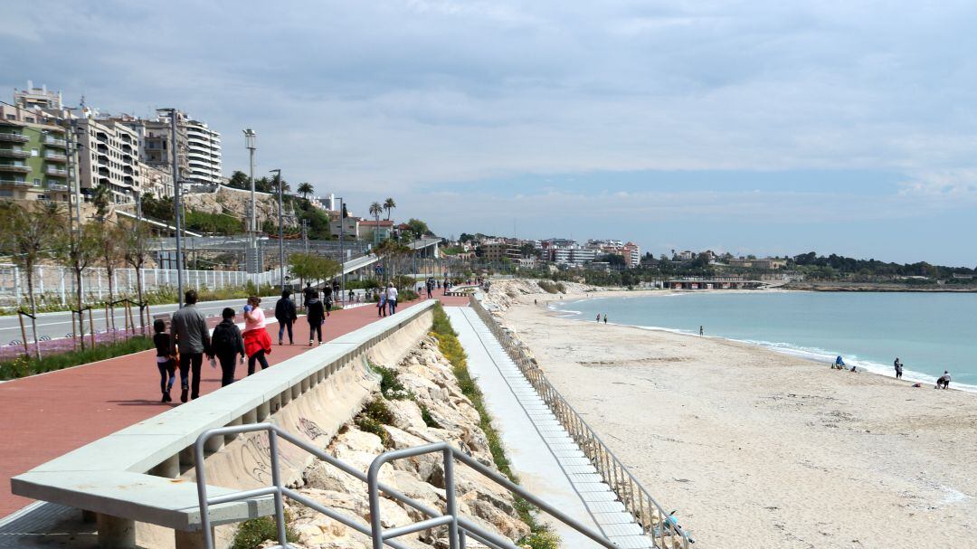 Pla general de diverses famílies passejant pel passeig marítim i a la platja del Miracle de Tarragona. 