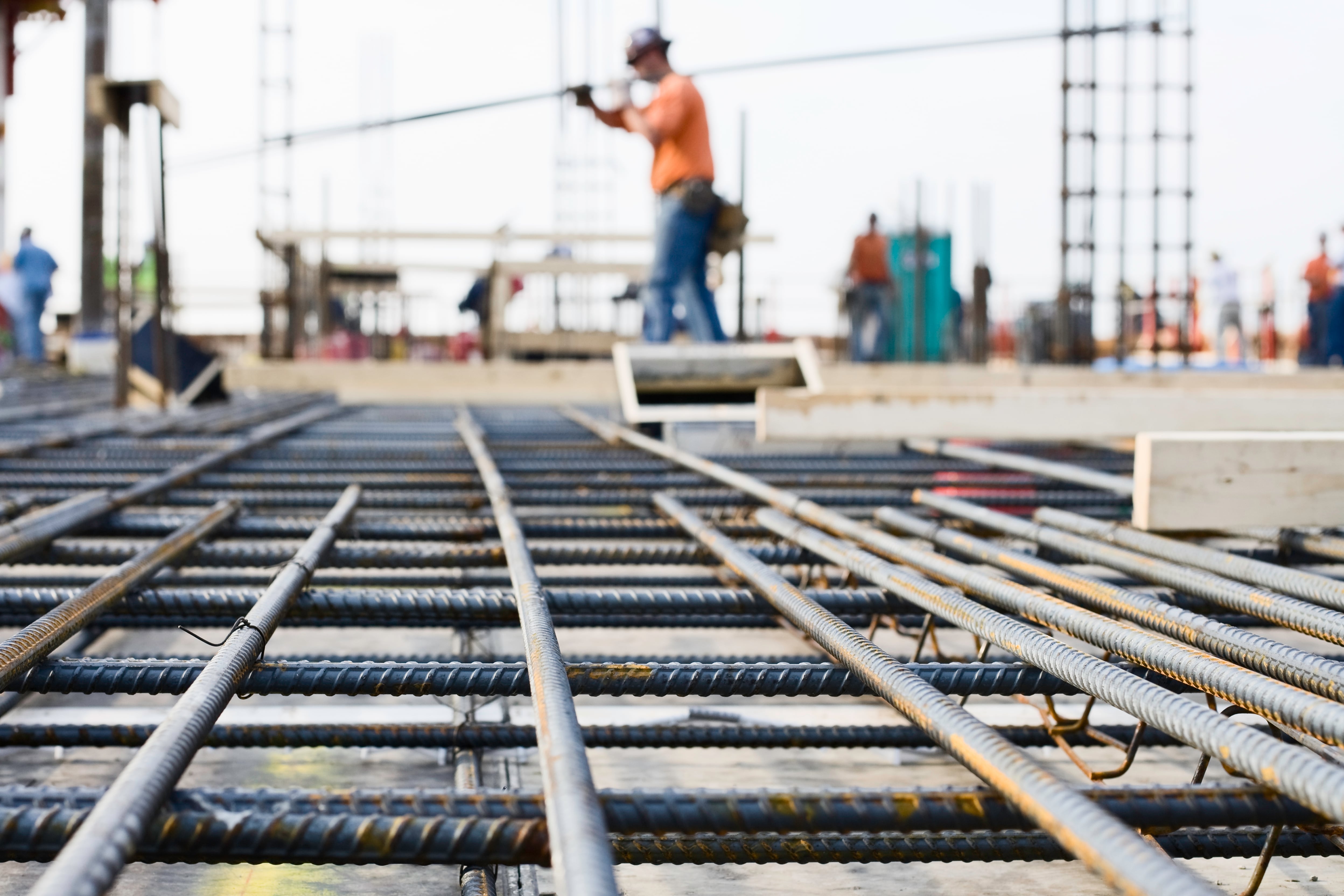 Malla de hierro en el suelo y, de fondo, un trabajador de la obra cargando material de construcción