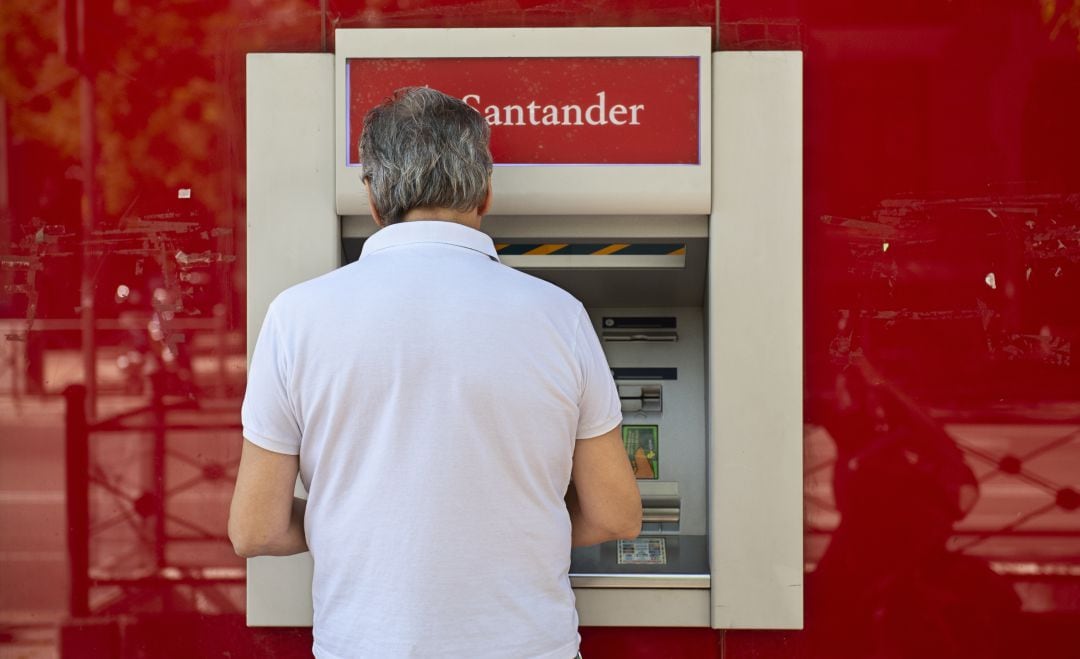 Un hombre realiza una gestión frente a un cajero del Banco Santander.