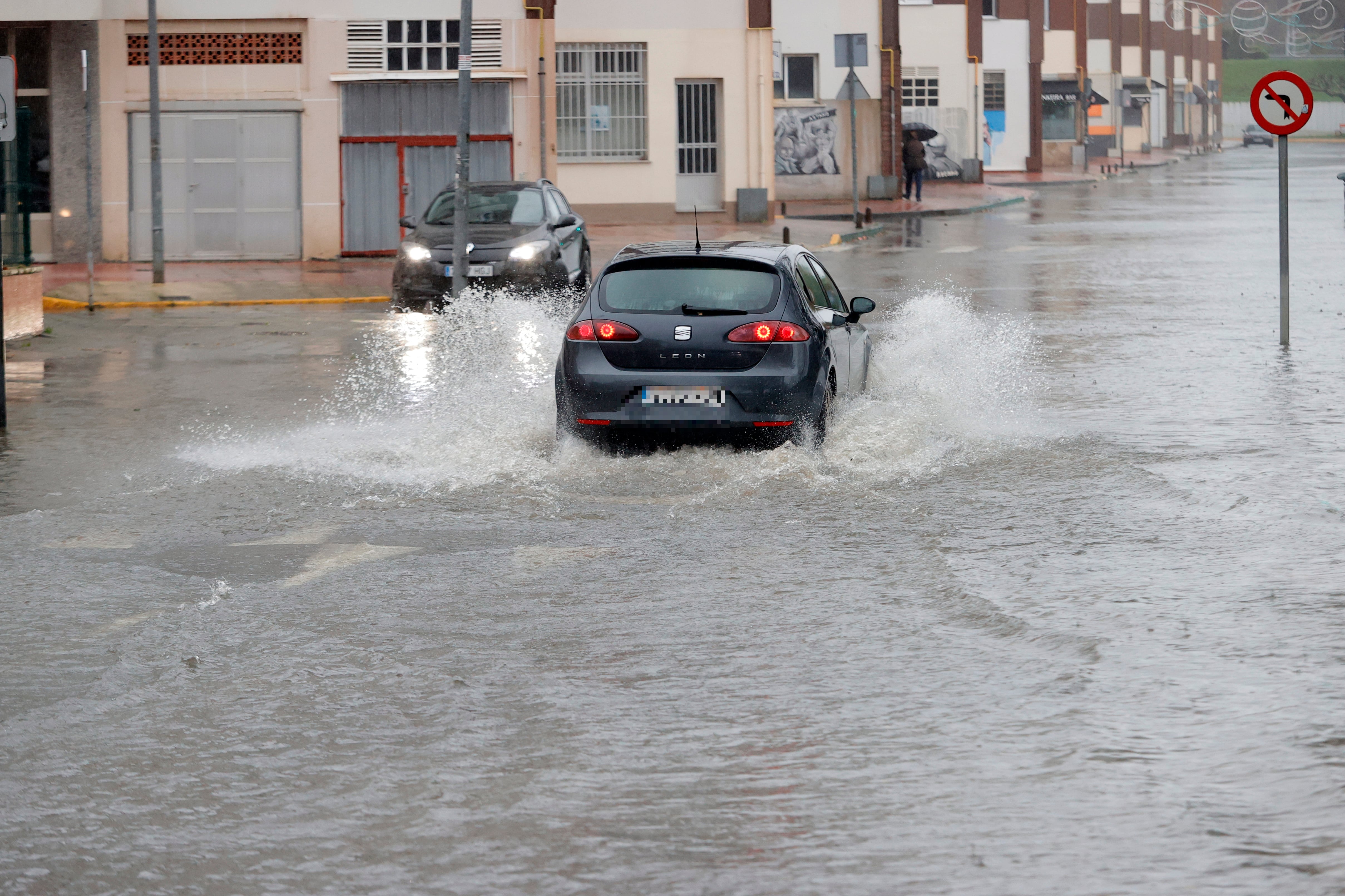 FENE (A CORUÑA), 23/12/2022.- Varios vehículos tratan de avanzar por el barrio de San Valentín, en la localidad coruñesa de Fene, inundada este viernes por las fuertes lluvias. Según cálculos de la agencia meteorológica Aemet, las lluvias acumuladas pueden alcanzar los 80 milímetros en 12 horas, por lo que la Xunta indica haber puesto en alerta naranja -el segundo de tres niveles- a las autoridades. EFE/ Kiko Delgado
