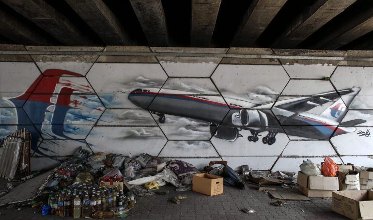 Un hombre descansa junto a un mural del vuelo desaparecido de Malaysia Airlines en Shah Alam a las afueras de Kuala Lumpur.