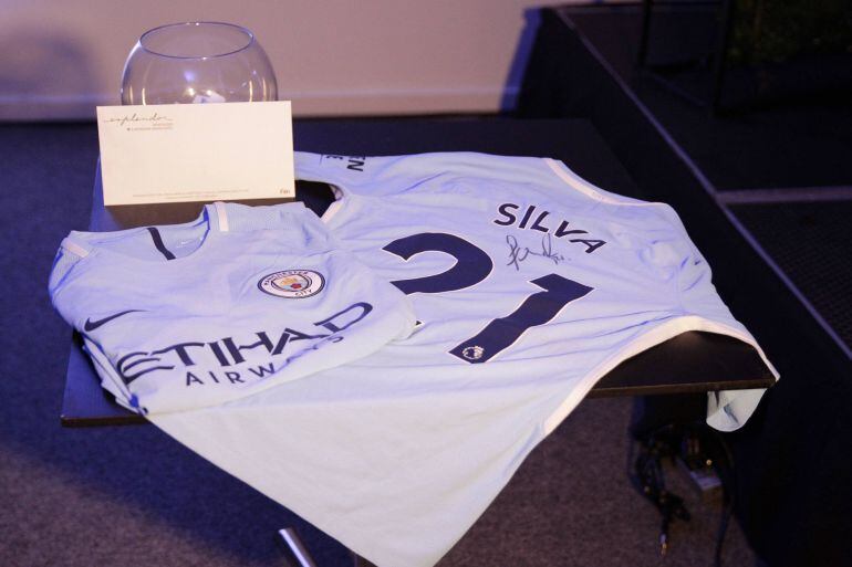 MON304. MONTEVIDEO (URUGUAY) - Vista de dos camisetas del Manchester City, una de ellas firmada por el jugador David Silva, que fueron sorteadas hoy, miércoles 25 de julio de 2018, en el marco de la charla &quot;El negocio del fútbol&quot;, en Montevideo (Uruguay). Gigliani dijo que el City Football Group, compañía en que se integra el Manchester City británico, tiene como objetivo ampliar el numero de equipos que posee y está &quot;explorando posibilidades en todos los continentes&quot;.