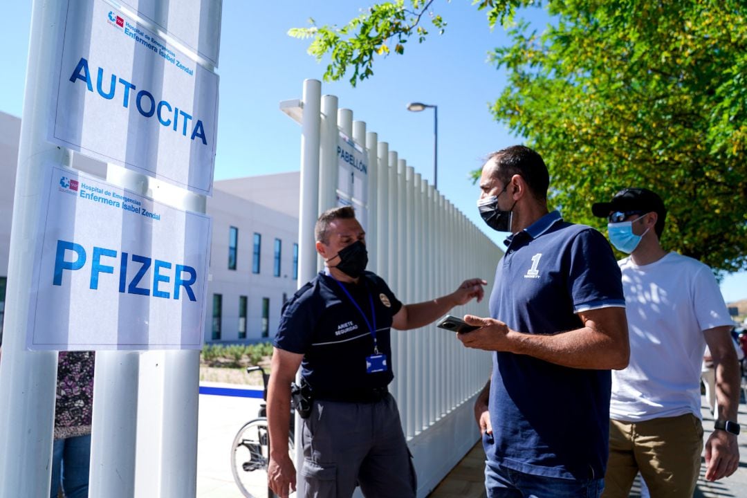 Un policía controla la entrada de varias personas a las afueras del Hospital público de emergencias Enfermera Isabel Zendal