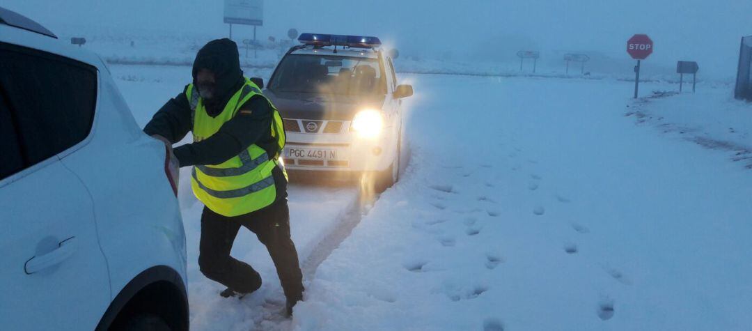 Un agente de la benemérita ayudando a un vehículo atrapado por la nieve