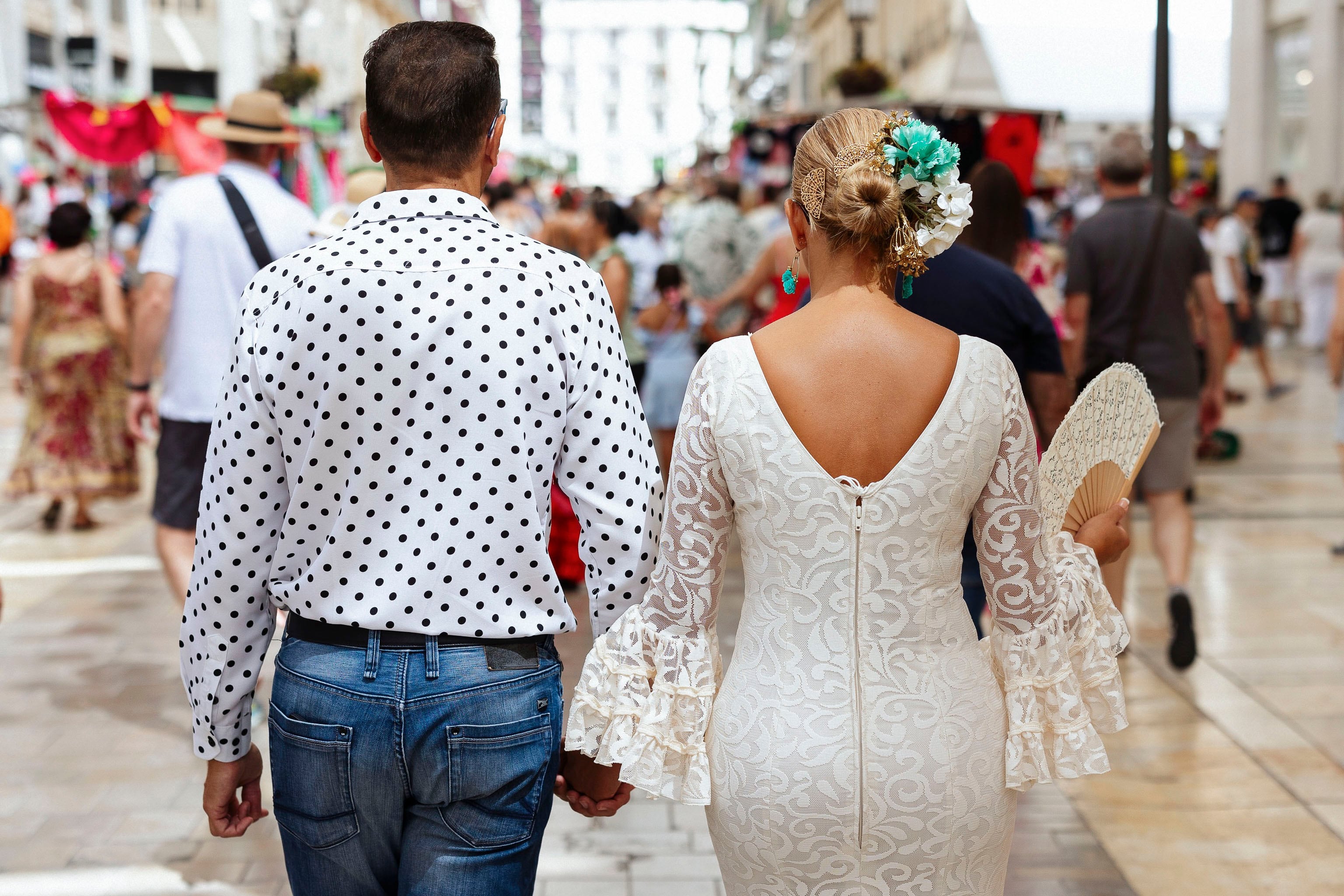 MÁLAGA, 24/08/2024.- Una pareja pasea por la calle Larios en la Feria del centro de Málaga que termina este sábado. EFE/Carlos Díaz
