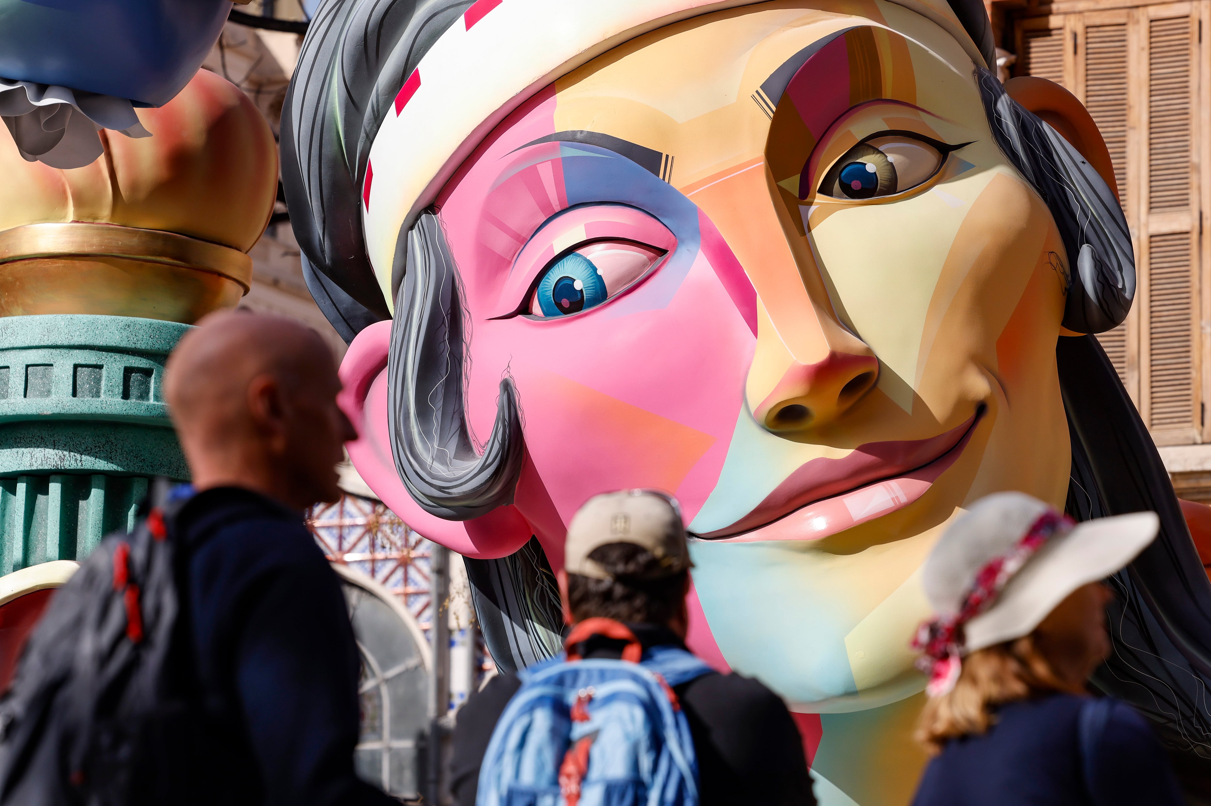 Varios turistas pasan ante una de las cerca de 400 fallas que se plantan en Valéncia y en las que los artistas falleros trabajan sin descanso a falta de dos días para que estén terminadas el próximo día 16 por la mañana. EFE/Ana Escobar