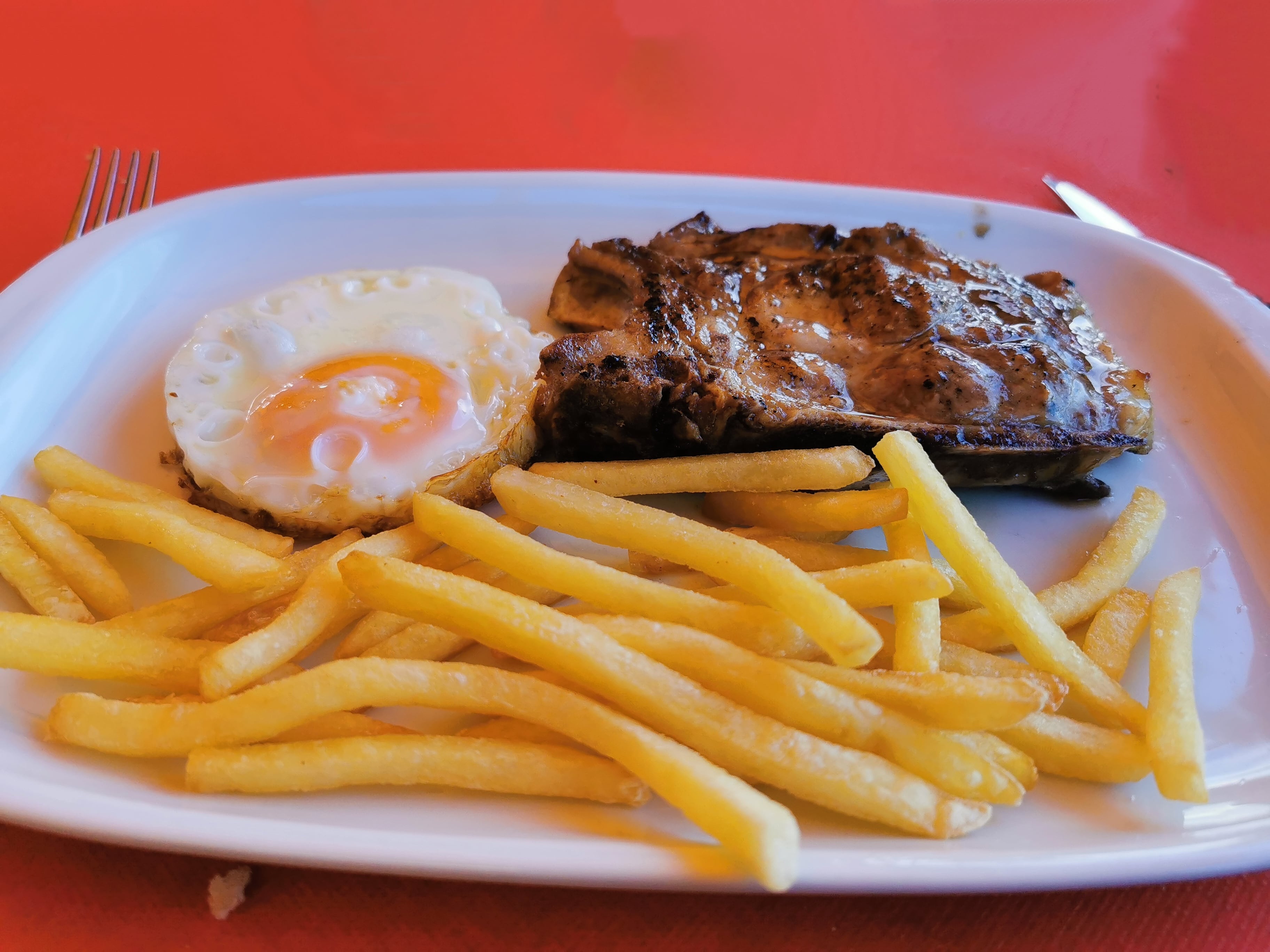 Plato combinado de cerdo, patatas y huevo frito.