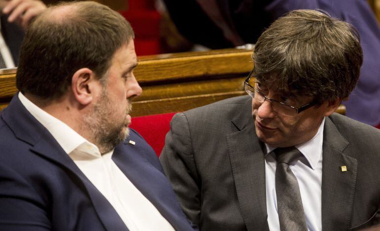 El presidente de la Generalitat, Carles Puigdemont, junto al vicepresidente Oriol Junqueras (i), durante el pleno del parlamento de Cataluña, el día después de aprobarse la reforma del reglamento de la cámara catalana