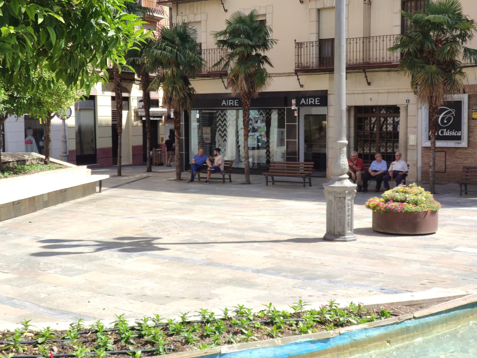 Personas descansan en los bancos, a la sombra, en la Plaza de San Ildefonso de Jaén