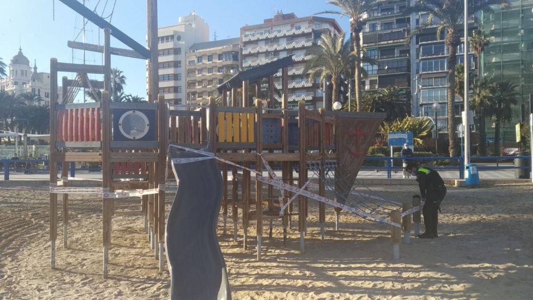 Un agente de la policía precinta los juegos en la playa de El Postiguet