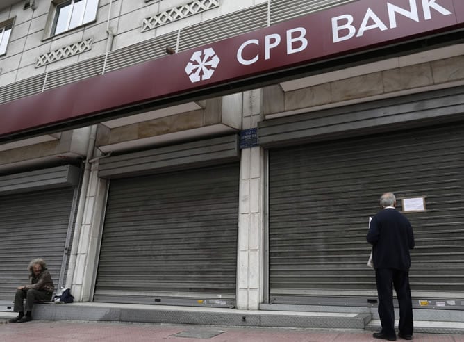 Un hombre lee una nota para los clientes del banco CPB informándoles de que permanecerá cerrado