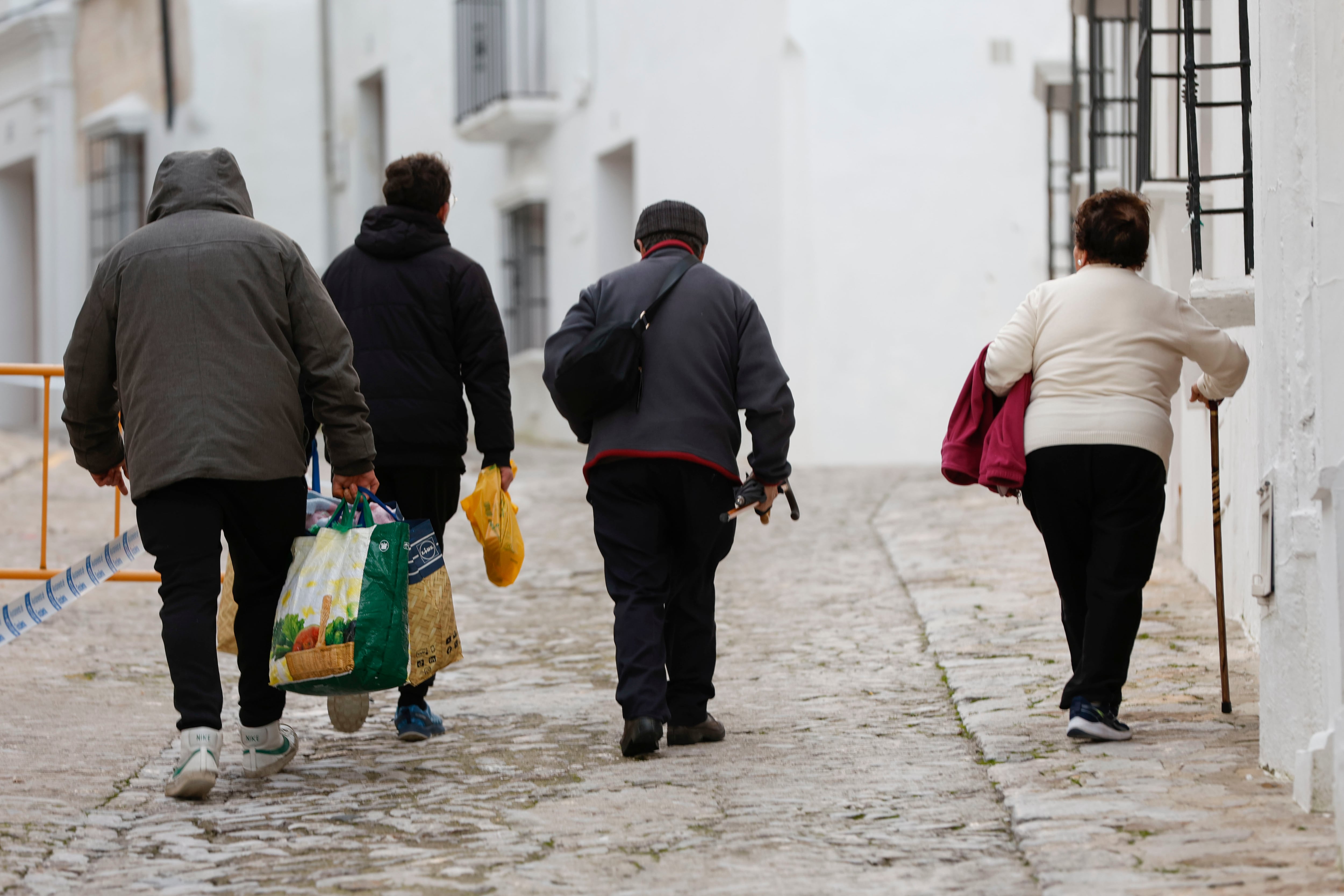GRAZALEMA (CÁDIZ), 16/02/2026.- Varias personas caminan por una calle de Grazalema este lunes. Un primer grupo de vecinos desalojados hace 11 días por el temporal en Grazalema (Cádiz) ha podido volver a sus hogares a partir de las 16:05 horas de este lunes, cuando la Guardia Civil ha permitido el acceso a una treintena de vehículos al municipio. EFE/ Jorge Zapata