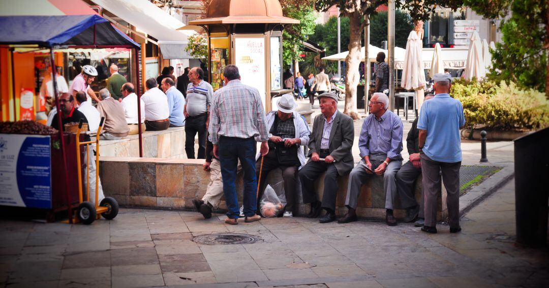 Un grupo de personas mayores sentadas en la plaza de la Constitución.