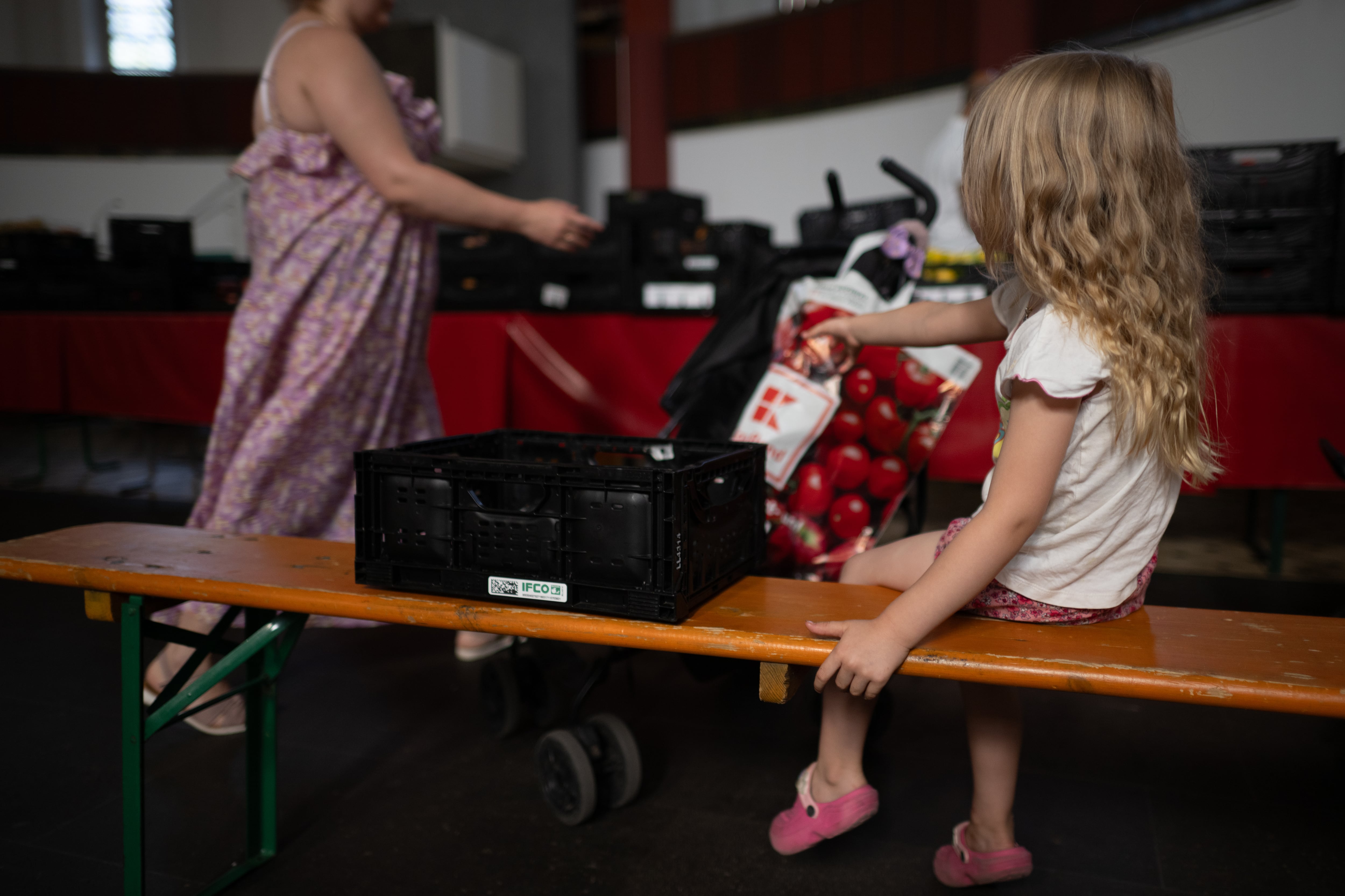 Una niña espera junto a su madre en una iglesia donde se reparten alimentos en Berlín