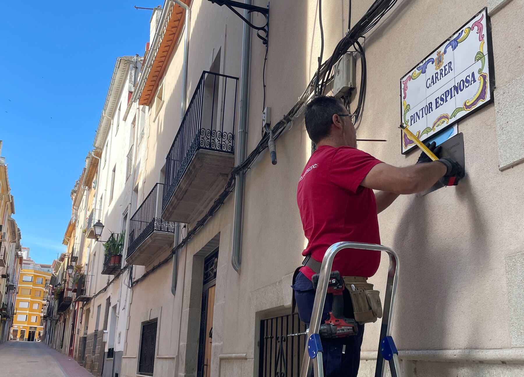 Un operario colocando una de las pequeñas placas. Ajuntament de Cocentaina
