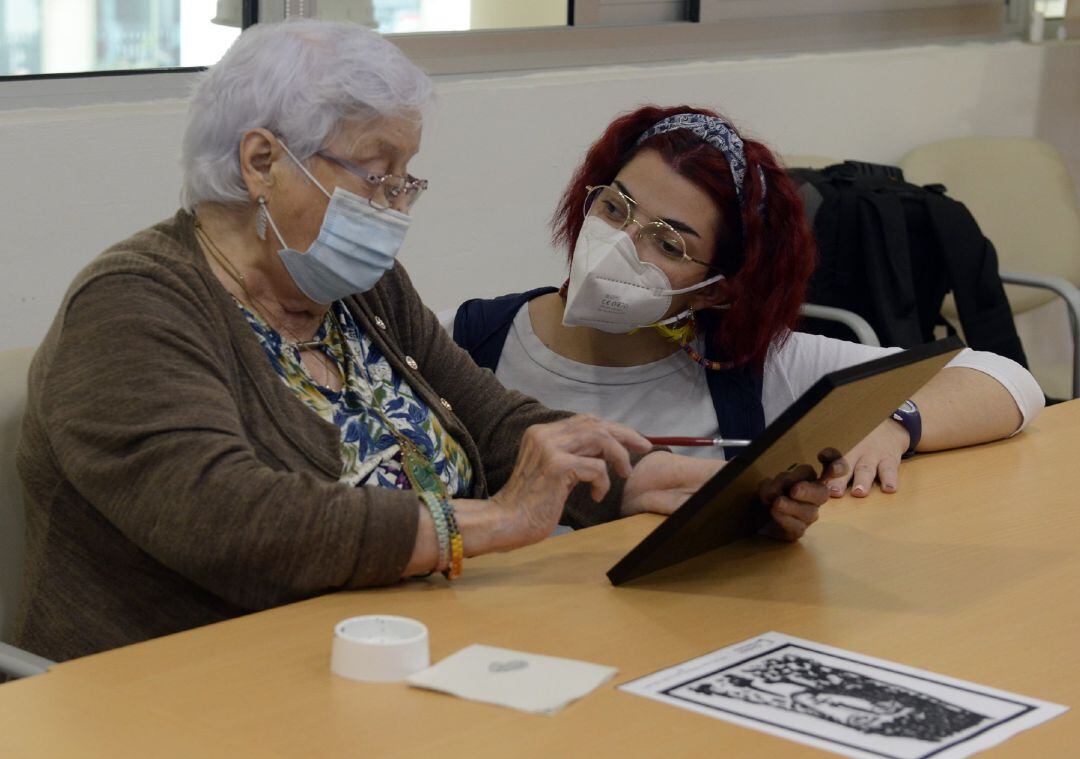 La trabajadora de una residencia de ancianos atiende a una interna.