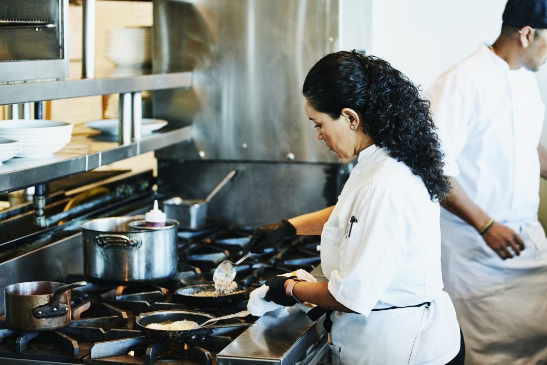 Una cocinera trabaja en los fogones de una cocina.