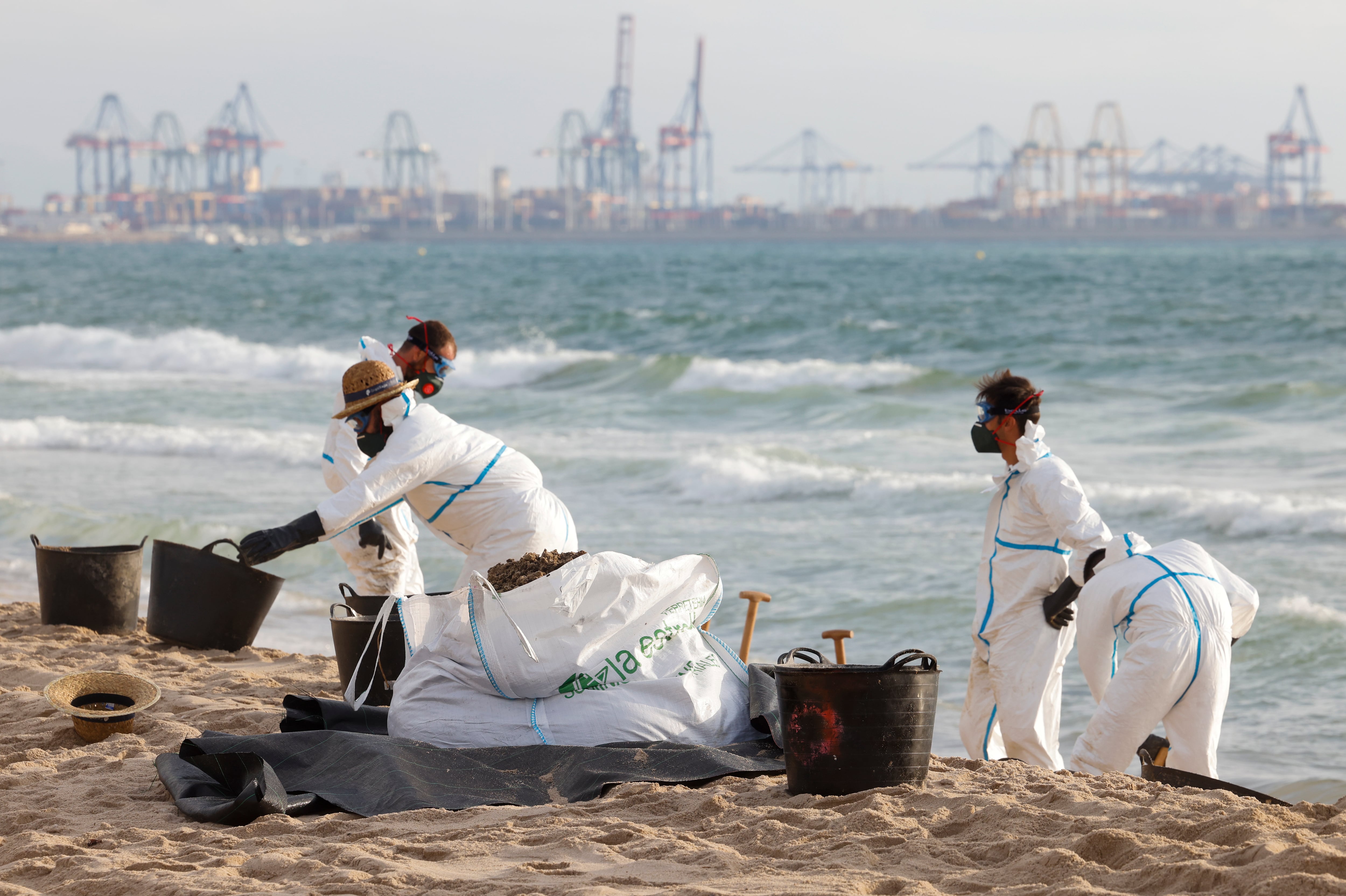 Varios operarios trabajan en la limpieza de la playa afectada por el vertido de hidrocarburos registrado este martes en tres playas del sur de la ciudad de València.